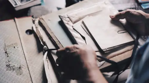 Close-up of a person's hands sorting through an assortment of old letters, envelopes, and documents. The materials are worn, suggesting age, and evoke a sense of nostalgia. Among the papers is information about a type of life insurance. The person appears to be organizing the items with care.