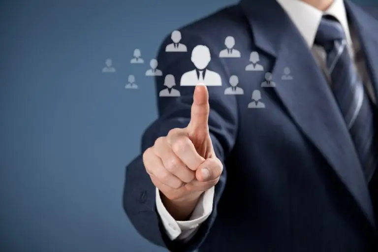 A person in a suit is pointing at a graphical representation of people icons. The semi-transparent icons are arranged in a cluster around the outstretched finger, symbolizing the selection or connection of individuals within a network, perfectly illustrating business succession planning.